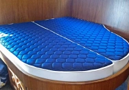 LAROMA TRAVEL Komfort-Matratzen in einer Schlafkoje auf einem Boot, individuell angepasst an die runde Form. Die Matratzen in blauem Bezug bieten innovative Stützzonen, optimale Belüftung und höchsten Schlafkomfort, speziell für den Einsatz auf Yachten und Booten entwickelt.